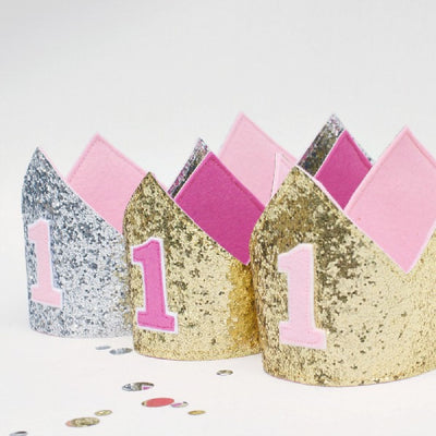 glitter birthday crown for kids - pictured in silver glitter with pink number 1 on the front, gold glitter with pink number 1 on the front for a first birthday
