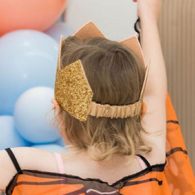 gold glitter birthday crown on a young child showing the elastic casing at the back of the crown